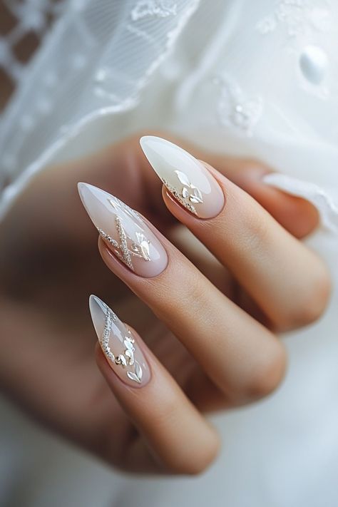 Hand with elegant, almond-shaped nails featuring a delicate, white floral design. Bride Nails With Rhinestones, Minimal Bridal Nails, Nails Design For Bride, Cute Wedding Nails The Bride, Rustic Wedding Nails For Bride, Almond Nail French Design, Wedding Nail Designs For Bride, Unique Bridal Nails, Wedding Nails For Bride Classy Bridal