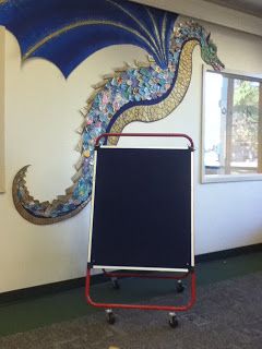 How in the world did they make this dragon? OMG-he is beautiful! Dragon Display Classroom, Fairytale Library Display, Fairy Tale Display, Medieval Classroom Theme, Fantasy Themed Classroom, Dragon Classroom Theme, Fantasy Classroom Theme, Fantasy Classroom Decor, Dragon Bulletin Board