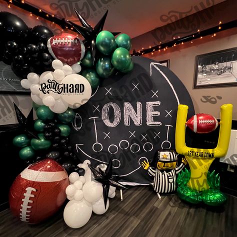 Football themed balloon for birthday boy turning one, 1st birthday party, green balloons, black balloons, white balloons, circle backdrops Football Theme Bday Decoration, First Down Party Decor, Giants Themed Birthday Party, Madden Themed Party, Football Birthday Party Balloons, Madden Football Birthday Party, First Year Down Football Birthday Balloons, First Year Down Football Birthday Backdrop, Football Themed Balloon Arch