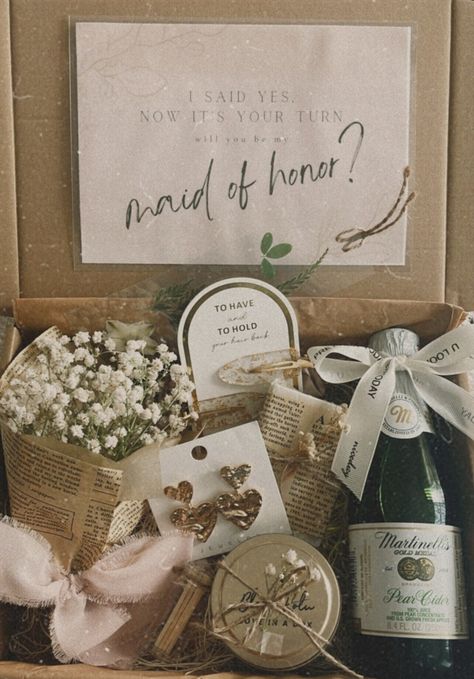 Our MOH proposal box is thoughtfully curated with the following items: (H)= Handmade - Petite bouquet of Baby Breath (H) - Double Golden Heart Earrings - Hair Clips - Goat Milk Soap (H) - Martinelli's Gold Medal Sparkling Cinder (H) - Floral Bookmark - Soy Wax Candle (H) -  Safety matches The gift can be shipped directly to the MOH by updating the name and address during checkout. Make sure to mark the order as "a gift" and leave a note saying who it is from. Notably, our candles and soaps are diligently cured before being made available for purchase. While we understand that orders may be placed swiftly, we feel it's essential to disclose that our candles and soaps typically undergo a two-week curing process. This process involves the gradual hardening of soy wax to ensure an even dispers Maid Of Honor Gift Basket, Ideas To Ask Maid Of Honor Gift Boxes, Maid Of Honor Proposal Sage Green, Mom Maid Of Honor Proposal, Simple Bridal Party Proposal, Ways To Ask Ring Bearer To Be In Wedding, Maid Of Honor Proposal Best Friend, Made Of Honor Gifts From Bride, Personal Bridesmaid Proposal