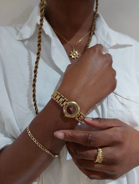 Picture of a black girl wearing different types of gold jewelry (gold bracelet, gold ring, gold watch and gold necklace). She is posing with her hands crossed over a crisp white shirt. Jewelry Inspo Black Women, Gold Bracelet For Women Aesthetic, Jewelry Accessories Black Women, Beige Aesthetic Black Woman, Jewellery On Black Women, Black Woman Accessories, Stacked Rings Black Women, Dark Skin Jewelry, Gold Bracelet Stack Black Woman