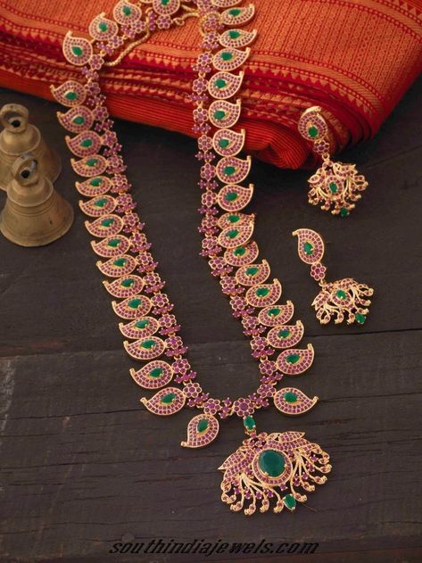 This imitation ruby emerald haram set is made of mango shaped motifs, each studded with tiny rubies and oval shaped emeralds. Kempula Haram Designs, Temple Indian, Mango Haram, Mango Mala, Haram Designs, Indian Bridal Jewellery, Traditional Indian Jewellery, Long Pearl Necklaces, South Indian Jewelry