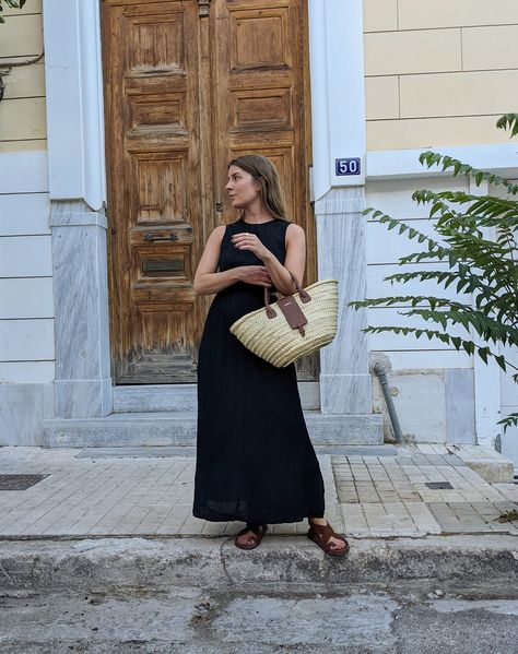 A women stands on the pavement in front of a large wooden door. She wears a sleeveless black dress and brown sandals, and a carries a basket bag on her arm. Long Black Summer Dress, Black Dress For Summer, The Minimalists, Black Summer Dress, Summer Vacation Outfits, Summer Black Dress, Timeless Dress, Dress For Summer, Long Summer Dresses