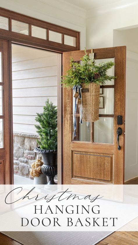 front door entryway with wood door and christmas hanging door basket with pine and cedar and pine tree in planter urn. Front Door Basket Ideas, Front Door Hanging Basket, Hanging Door Basket, Door Hanging Basket, Front Door Baskets, Door Basket, Wreath Hangers, Basket Wreath, Front Door Wreaths