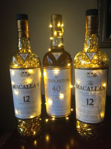 Macallan Scotch whiskey bottle centerpieces party decorations, 40th birthday. Large (empty) 1.75 L macallan bottles filled with fairy lights and gold metallic shred. Balloon Topiary, 40th Bday Ideas, Birthday Party Decorations For Adults, Bottle Centerpieces, Led Fairy String Lights, Glitter Glasses, 70th Birthday Parties, Birthday Centerpieces, Cigars And Whiskey