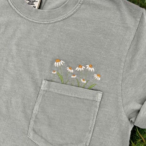 A pocket full of daisies! These embroidered floral pocket tees make the perfect Spring/Summer shirts! Check out our page for these shirts in more designs! **shirt colors may vary slightly from shirt to shirt depending on dye. please use the color chart in the last picture for a truer color** ORDERING & SHIPPING *Your item will be shipped within 5-7 business days. *Please allow 2-5 business days to receive your item, more time may be necessary depending on holidays. *We do not accept returns/refu Embroidered Wildflowers, Embroider Ideas, Embroidered Denim Shirt, Pocket Tees, Embroidered Pocket, Embroidery Tshirt, Floral Embroidery Patterns, Floral Pocket, Embroidery On Clothes