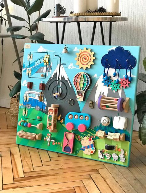 21 toddler busy boards for fine-tuning motor skills | Mum's Grapevine Wall Mounted Busy Board, Handmade Busy Board, Activity Wall For Toddlers, Diy Sensory Boards, Baby Zintuiglijk, Fidget Board, Perlengkapan Bayi Diy, Baby Activity Board, Montessori Board