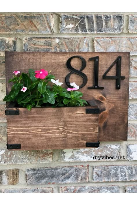 You can add a lot of curb appeal to your home with this DIY house number planter. Switching out the flowers to reflect the season will create a warm welcome for your guests.       What you’ll need for a DIY house number planter:       1 x 12 x 4 board (shortest I could find)–this will be the base  (1) 1″ x 6″ and (1) 1″ x 4″ (you’ll use less than 2′ so get shorter boards)  house numbers  measuring tape/pencil  sandpaper  wood conditioner/stain  wood glue  polyurethane  hammer and… Wood House Number Sign Diy, House Numbers With Planter, Wooden House Number Sign Diy Wood, House Number Succulent Planter, Wood House Number Sign With Planter, House Number Planter, Unique House Numbers, Wood Conditioner, Modern House Numbers Sign