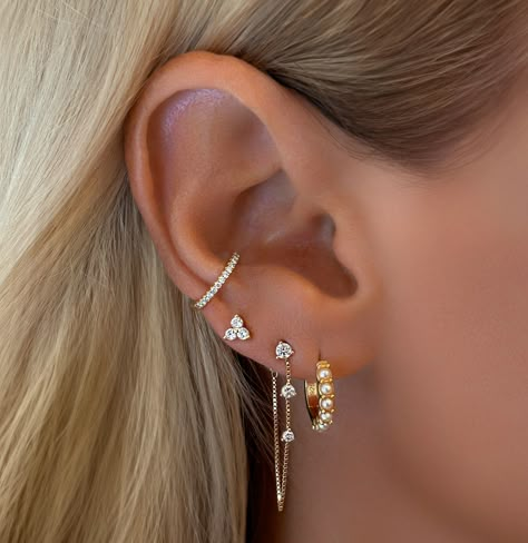 Tips For Curating the Perfect Dainty Feminine Ear Stack: There’s something magical about a well-curated ear stack—it’s like creating a miniature gallery on your ear. 1. Start with the Stud The foundation of any great ear stack is a chic and understated stud. Opt for something that speaks to your personal style—whether it’s a tiny diamond, a pearl, or a delicate gold ball. This piece anchors the look, adding a subtle sparkle that doesn’t overpower the rest of the stack. 2. Add a Huggie for... Earring Stack Ideas Mixed Metals, Stacked Jewelry Earrings, White Gold Earring Stack, Stackable Earring Ideas, Ear Design Piercing, Dainty Earring Stack, Ear Mapping, Miniature Gallery, Earring Huggies