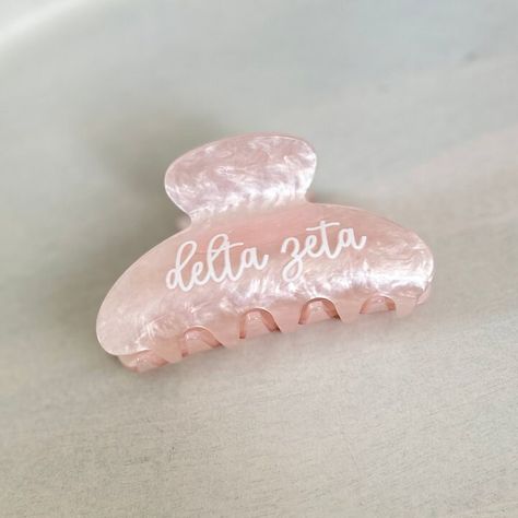 A custom hair clip is a beautiful and practical gift for the sorority girl! Personalized on one side with high-quality vinyl, it's sure to be a well-used gift! ~TO ORDER~ Choose your sorority from the drop-down list.  ~ PRODUCT DETAILS ~ 3-1/4" wide x 2.5" tall with heavy-duty claw design Personalized in high-quality printed vinyl on ONE side of the clip. Add a hair clip with a cute cosmetic bag and we'll bag together to make a cute sorority gift! Hair Clip/Personalization Colors: Delta Zeta: light pink/white letters ~ OTHER INFORMATION ~ Normal turnaround varies by item and is indicated in the shipping information. See shop announcement for variations. If you need an item sooner, please send a message before placing your order.  Happy Thoughts Gifts is a Greek-licensed provider. Only the Delta Zeta Sorority, Personalized Clipboards, Big Little Basket, Claw Design, Sorority Big Little, Kappa Alpha Theta, Alpha Chi Omega, Sorority Girl, Delta Zeta