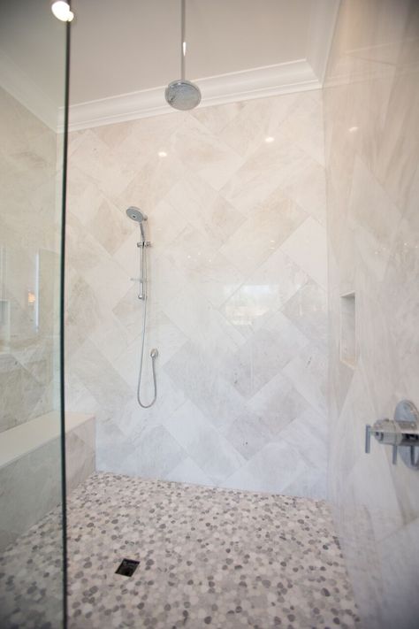 Contemporary bathroom with walk-in shower with bench, marble tile in a herringbone pattern and pebble floor. Large Tile Herringbone Shower Wall, Bathroom Shower Tile Ideas Walk In Pebble Floor, Walk In Shower Pebble Floor, Bathroom Shower Tile Ideas Walk In Herringbone Pattern, Large Herringbone Shower Tile, Pebble Floor Bathroom, Pebble Floor Shower Ideas, Pebble Floor Shower, Shower With Pebble Floor