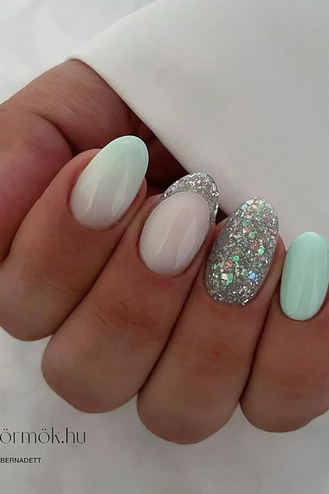 Elevate your style with these almond-shaped nails showcasing a chic blend of pastel and sparkle. Two nails dazzle with a dense silver glitter overlay, capturing light and attention, while the remaining complement with a soft mint green and subtle ombré transition to opaque white, exuding a fresh, serene vibe. Perfect for adding a splash of spring elegance to any look. 💅✨  // Photo Credit: Instagram @_bettynails_ Mint Green Glitter Nails, Mint Green And Silver Nails, Mint Christmas Nails, Mint Green Christmas Nails, Mint Green And White Nails, Pastel Mint Nails, Green And Glitter Nails, Light Green Nail Ideas, Glitter Green Nails