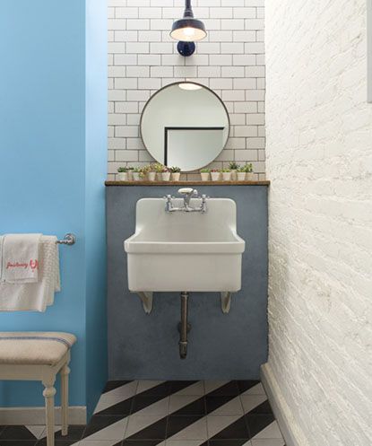 Bathroom sink area with subway tile, brick wall and black and white striped floors