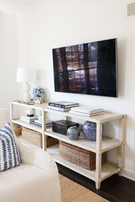 Styling a console table can also give your room a new look, and is a great opportunity to add personality to your home. When choosing a piece of furniture for below your TV, think about how you’ll use it. We chose an open console and even though there aren’t cabinet doors for storage, it’s been perfect for us. Styling Tv Console Shelves, Tv Console Decorating Open Shelves, Tv Over Console Table Family Rooms, Open Shelf Tv Stand Decor, Tv Console Cabinet Living Room, Tv Stand Decor Shelves, Tv Mounted Above Console Table, Open Console Styling, Table Below Tv Mounted Tv