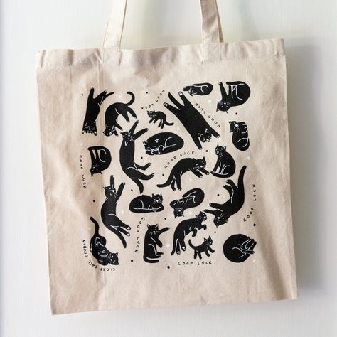 Limited edition of 50 heavy canvas totes with "GOOD LUCK" and black cats screen printed on one side in black and white. 16 x 15 in canvas bag This product is designed by me and printed sustainably by hand in Baltimore by Black Collar Press on 100% cotton totes made in the US Each item is shipped in a soft envelope. 10% of your purchase will be donated Cat Screen Print, Cat Tote Bag Design, Linocut Tote Bag, Lino Print Tote Bag, Canva Business Ideas, Black Tote Bag Design, Canvas Tote Bag Design, Cat Shirt Design, Cool Tote Bags