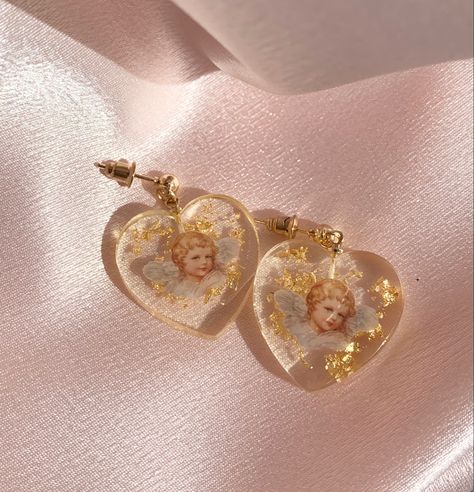 our gorgeous cherub resin gold flake earrings with a golden stud! aesthetic earrings that glimmer in the sun. available 1/20. Website link will be added soon! Resin Earrings Aesthetic, Resin Aesthetic Ideas, Aesthetic Resin Jewelry, Resin Jewelry Aesthetic, Aesthetic Resin Art, Cherub Earrings, Resin Aesthetic, Stud Aesthetic, Aesthetic Earring