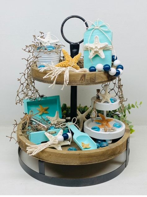 Rustic coastal beach tiered tray! Bundle includes: Tier Tray Filler 1-10 inch Eucalyptus Stem 2- 10 inch Fish Net Fillers 1- Brown Sugar Starfish 2- White Starfish 6- Aqua Blue Glass Accents 1- Mini Two Tiered Tray w/ 2 mini bottles filled with seashells, 1 mini brown sugar starfish and 3 aqua glass accents 1- Treasure Chest filled with fish net, 1 white starfish, 3 aqua glass accents, and 1 bottle filled with seashells 1- Mini Wooden Spoon w/mini brown sugar starfish 1 - Starfish Bead Garland 1 Mini Tiered Tray Decor, Bathroom Tiered Tray Decor, Bathroom Tiered Tray, Two Tiered Tray, Mini Tiered Tray, Summertime Decor, Beach Themed Crafts, Diy Beach Decor, Coastal Farmhouse Decor