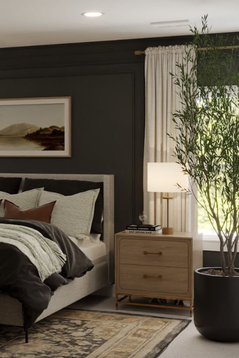 Modern bedroom with charcoal accent wall, beige bed linens, brass-accented nightstand, minimalist lamp, and potted indoor tree. Dark Charcoal Accent Wall Bedroom, Black And Natural Wood Bedroom Ideas, Moody Bedroom Color Schemes, Tricorn Black Accent Wall Bedroom, Organic Moody Bedroom, Charcoal Accent Wall Bedroom, Accent Wall Master Bed, Dark Master Bedrooms, Dark Grey Bedroom Walls