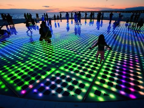 Croatian architect Nikola Baic’s LED light installation titled Saudao ao Sol, translated as Greeting to the Sun, is a remarkable piece of public art that efficiently incorporates technology. The circular floor installation consists of three hundred multilayered glass plates encasing solar cells that absorb sunlight during the day and come alive at night, putting on … Led Light Installation, Zadar Croatia, Light Art Installation, Art Lighting, Lighting Art, Modern Metropolis, Interactive Installation, Interactive Art, Solar Powered Lights