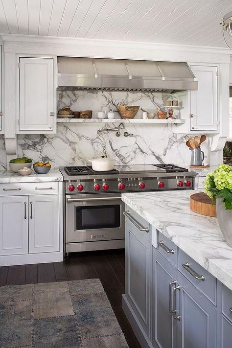 A stainless steel hood vent stands over a floating marble spice shelf lining a marble slab cooktop backsplash. Shelf Above Cooktop, Shelf Behind Stove, Cooktop With Downdraft, Cooktop Backsplash, Spice Basket, Stainless Steel Hood Vent, Stove Design, Kitchen Cooktop, Grey Kitchen Floor