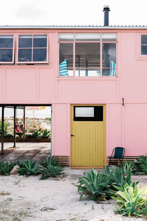 Sister duo Sarah Hall and Emma Read (@readandhall) renovates Love & Mutiny into a unique, fully-equipped beach house. The outdoor facade boasts beautiful and vibrant colours. Pink beach house, yellow door and sand at your doorstep. Just looking at this will relieve your stress. 1950s Beach, Brick Extension, Pink Coastal, Coastal Cabin, Beach Shacks, Green Flooring, Top Architects, Beach Retreat, Beach Shack