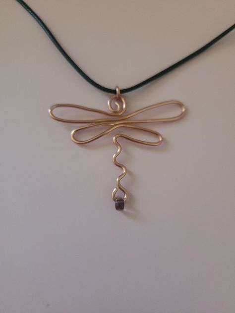 This is an image of an abstract wire dragonfly pendant made of copper wire with a tiny lilac teardrop bead at the bottom of the dragonfly's tail.  It is on a black cord necklace Wire Jewelry Dragonfly, Wire Art Necklaces, Pierced Jewelry Patterns, Dragonfly Jewelry Diy, Wire And Bead Dragonfly, Wire Bead Necklace Diy, Words Made Out Of Objects, Dragonfly Wire Wrap, Wire Dragonfly Tutorial