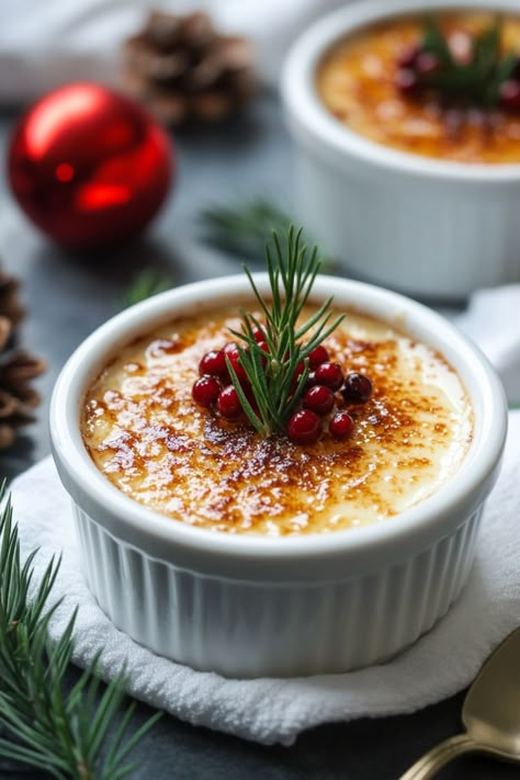 Creme brulee topped with red berries and a sprig of rosemary, surrounded by holiday decorations. Christmas Dessert Elegant, Holiday Creme Brulee, Eggnog Desserts Christmas, Christmas Dessert In A Cup, Eggnog Creme Brulee, Flavored Creme Brulee, Christmas Creme Brulee, Christmas Panna Cotta, Christmas Dessert Aesthetic