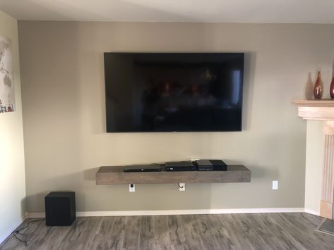 Custom floating shelf used as a minimalistic media console shelf.  Six-feet long by one-foot deep to accommodate an Xbox One and Xfinity cable box.  Stained with Briarsmoke by Verathane.  75” TV added for perspective :) Tv And Xbox On Wall Mounted Tv, Xbox Shelf Ideas, Under Tv Ideas, Mounted Tv Decor, Floating Shelf Under Tv, Custom Floating Shelves, Tv Ideas, Console Shelf, Candle Holders Wall Decor