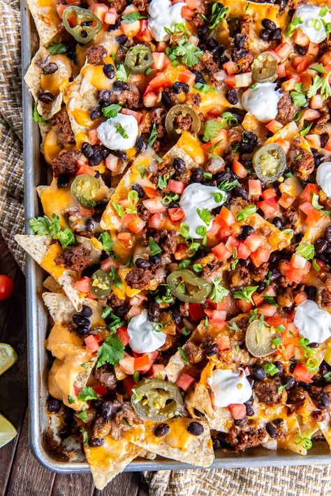 These sheet pan Super Nachos are loaded with ground beef, black beans, homemade nacho cheese sauce, and plenty of freshly shreddded cheese. Just pile on your favorite toppings and dig in! Loaded Nacho Dinner, Nachos Recipe Sheet Pan, One Pan Nachos, Yummy Nachos Recipe, Fancy Nachos, Nacho Sheet Pan, Best Loaded Nachos Recipe, Loaded Beef Nachos, Nacho Dinner Ideas