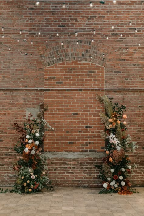 Wedding Brick Wall Decor, Brick Wall Floral Backdrop, Brick Wedding Ceremony, Exposed Brick Wedding Decor, Dried Flower Arch Wedding, Earth Tone Spring Wedding, Earth Tone Flower Arrangements, Fall Wedding Alter Decor, Floral Columns Wedding