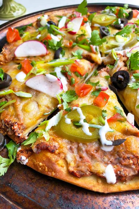 Cheesy pizza and classic nachos unite in this zesty recipe that layers garlicky black beans, shredded cheese, and salsa. Your favorite nacho toppings like briny black olives, sour cream, and pickled jalapenos also show up to the party! Get the recipe now on Foodal. #nachos #pizza #foodal Nacho Pizza Recipes, Nacho Pizza, Classic Nachos, Black Bean Spread, Taco Dinner Recipes, Calzone Recipes, Mexican Chilli, Nacho Toppings, Fish Taco Sauce