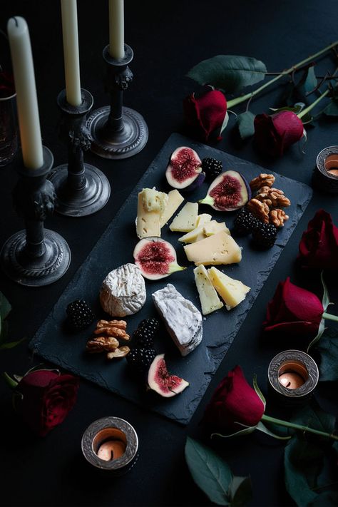 Slate cheese board with assorted cheeses, figs, walnuts, and blackberries, surrounded by gothic candle holders and deep red roses, illuminated by dramatic, low lighting. Black Cheese Board, Elegant Cheese Board, Goth Charcuterie Board, Gothic Charcuterie Board, Fancy Cheese Board, Cheese Board Ideas, Dark Elements, Vampire Party, Wine Ideas