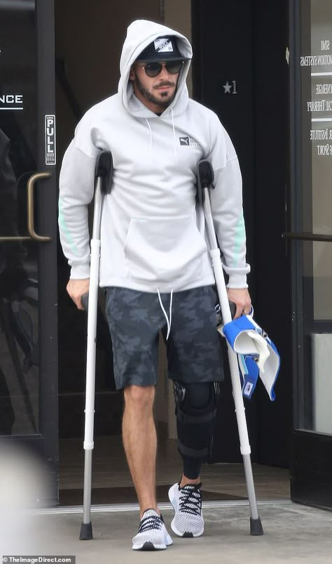 A little help: The movie star kept a low profile in a hoodie and sunglasses as he walked o... Hip Brace, Love Feeling Images, Celebrity Shoes, Leg Braces, Camouflage Shorts, Airplane Window, Knee Surgery, Broken Leg, Popular People