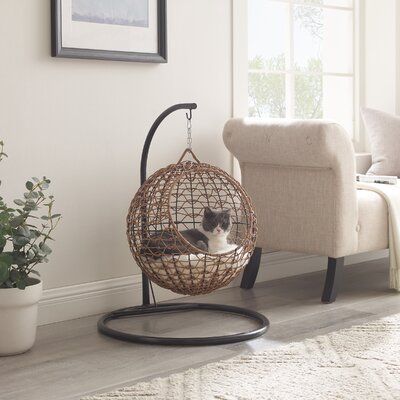 The Hanging Cat Condo combines a soft, cushioned enclosure with the sensation of gentle rocking to help your pet feel safe and secure. The included removable cushion is perfect for outdoor use while the added plush pillow cover will provide extra comfort for indoor use. Fashioned from rattan-style wicker in a selection of neutrals, the will fit seamlessly into any home. Sam's Pets Color: Brown Sam's Pets 35.04" Cat Bed in Brown | Size 35.04" L x 23.62" W x 35.04" H | AllModern Cozy Cat Furniture, Boho Cat Bed, Cool Cat Furniture, Pet Home Design, Cat Beds Cute, Cat Set Up Ideas, Cat Furniture Aesthetic, Cute Stuff For Cats, Cat House Decor