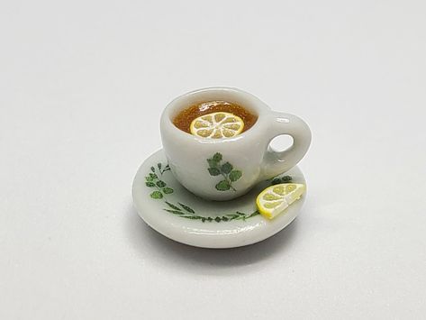 Life is like a cup of tea - to be filled to the brim and enjoyed with friends! A miniature ceramic cup of tea decorated with a lemon slice and a eucalyptus print. The saucer is attached and is also decorated with a eucalyptus pattern and a half lemon slice.   *Measurements: cup - 10mm diameter & 8mm height, saucer - 15mm diameter *Ready to ship. *Not intended as a toy for children. CARE INSTRUCTIONS: 1. Display and store your miniatures and jewelry in a dry, clean place away from direct sunlight Clay Tea Cup, Ceramic Miniatures, Cup Clay, Eucalyptus Pattern, Eucalyptus Print, Miniature Polymer Clay, Ceramic Tea Cup, Jewelry Safe, Lemon Slice