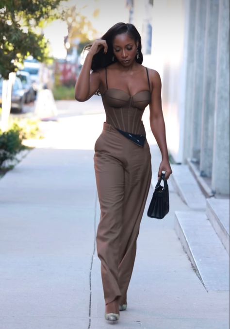 Woman walking in New York wearing a brown corset jumpsuit and a black hand bag Corset Top Jumpsuit, Brown And Gold Outfits For Black Women, Brown Semi Formal Outfits For Women, Black And Brown Dress, Neutral Party Outfit, Nude Corset Outfit, Corset Jumpsuit Outfit, Brown Corset Top Outfit, Nude Outfits For Black Women