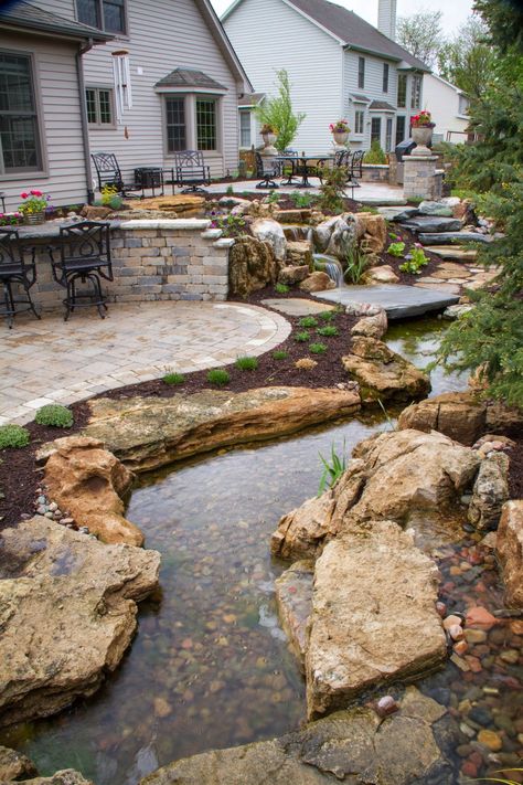 Stepping stones descend from the patio in the background, winding their way to the lower level, inviting visitors to explore the twists and turns of the stream and waterfalls. Kolam Koi, Taman Air, Garden Waterfall, Pond Waterfall, Pond Water Features, Pond Landscaping, Backyard Water Feature, Waterfalls Backyard, Pond Design