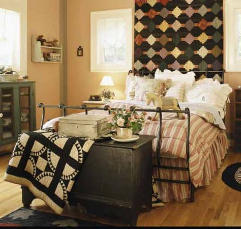 From allpeoplequilt.com   Hang a Headboard  A Log Cabin quilt extends the drama of this bed when it’s hung as a headboard instead of draped across the top. Purchased bedding complements the quilt but stills allows the quilt to be the focal point of the room. A Crown of Thorns quilt draped over a trunk at the foot of the bed pulls it all together.  More to check out: Fabric-Free Quilts,   Traditions Remembered, Quilting Design Gallery Quilt Hung Behind Bed, Dressing A Bed, Plant Lamps, Quilt Decor, Iron Beds, Primitive Bedroom, Vintage Decorating, Quilt Display, Black And White Quilts