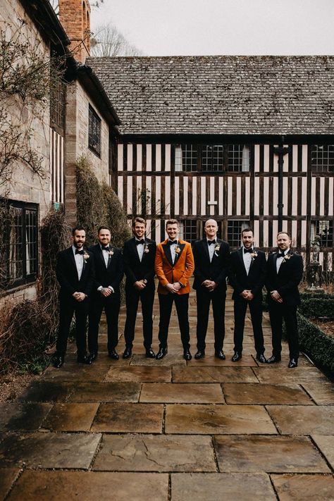 Groomsmen wearing classic black grooms suits with bowties standing with groom in crushed burnt orange velvet grooms blazer, black bowtie and black suit trousers outside Brinsop Court wedding venue | Jessica Grace Photography Burnt Orange Bridesmaid Dresses With Groomsmen, Black And Orange Tuxedo, Black Wedding Dress Orange Bridesmaids, Black Orange Wedding Theme, Rust Orange And Black Wedding, Black And Orange Fall Wedding, Burnt Orange Tuxedo Wedding, Black And Orange Wedding Theme, Burnt Orange Groomsmen Attire