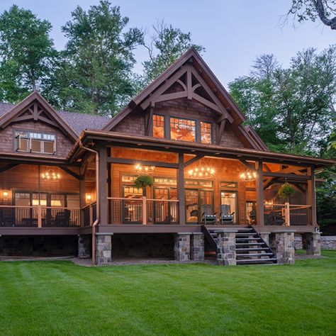 A deep wrap-around porch resting on stone pillars dominates the lakeside of this home overlooking a pristine Adirondack lake. Mountain House Wrap Around Porch, Stone House With Wrap Around Porch, Rustic House Plans With Wrap Around Porch, Homes With Big Porches, Rustic Wrap Around Porch, A Frame With Wrap Around Porch, Country House With Wrap Around Porch Farmhouse, Ranch Home Wrap Around Porch, Rap Around Porch House