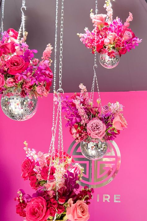 Hanging Disco Ball with Pink Floral Arrangements in front of a magenta wall with a silver EMPIRE logo Disco Bouquet, Barbie Flower Arrangement, Disco Ball Floral Arrangement, Disco Ball Flower Arrangements, Brunch Centerpiece Ideas, Disco Party Centerpiece Ideas, Disco Ball Centerpiece Ideas, Barbie Centerpieces Ideas, Botanical Color Palette