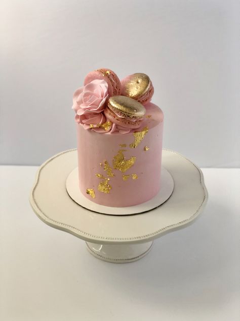 Small pink cake with gold leaf details on the front. There are three pink macarons on top with gold painted on them. Next to that is also a pink sugar rose. Cake Decoration With Macaron, 4 Inch Birthday Cake Ideas, Pink Mini Cakes Birthday, Pink Macaroon Cake, Pink Macaron Cake, Macarons Birthday Cake, Pink Cake With Macarons, Small Birthday Cake For Women, Small Cakes Ideas Minis