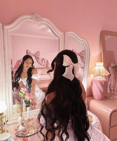 pretty girl with black hair and a pink bow wearing a white dress and a necklace jewelry looking at her desk mirror vanity that has a pink rose,plates that have coquette aesthetic and she's in a pink themed room Pink Princess Aesthetic, Pretty Pink Princess, Pink Lifestyle, Princess Core, Pink Life, Pink Girly Things, Pink Vibes, Princess Aesthetic, Pink Bedroom