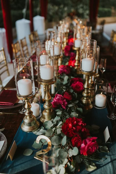 A navy table runner was topped with a garland of eucalyptus and scarlet peonies, as well as many candles on gold stands. Moody Flowers, Kings Table, Wedding Altar, Pro Tennis, Floral Runner, Candles Photography, Tafel Decor, Eucalyptus Garland, Wedding Table Flowers