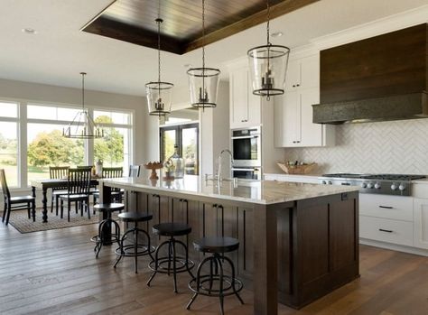 This kitchen features white walls and hardwood floors together with a large center island with marble countertop lighted by glamorous pendant lights set on the tray ceiling. Kitchen Tray Ceiling, Tray Ceiling Kitchen, Gossamer Veil, Living Room New York, Classy Kitchen, Wood Island, Kitchen Tray, Kitchen Remodel Design, Tray Ceiling