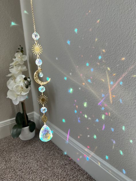 Beautiful celestial sun catcher made with premium materials like 18k gold plated chain, raw brass sun components, aurora borealis crystals and a large 50mm teardrop AB crystal. Length is approximately 14mm Suncatchets/ light catchers are a great way to let someone know that they are your sunshine ✨ What better gift than rainbows and sparkles?! Sun Catcher Bedroom, Sun Catcher Crystal, Dream Catcher Crystals, Light Catchers Diy, Sun Catchers Diy How To Make, Spiritual Room Ideas, Dream Catcher Light, Sun Catchers Diy, Celestial Room Decor