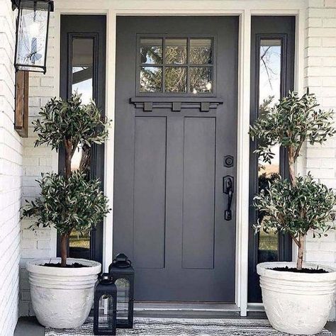 Dark grey introduces a sleek and sophisticated look, ideal for homeowners seeking an elegant yet understated entrance. This classic color enhances the charm of cottages and farmhouses alike, providing a refined touch without being overly bold. The versatility of dark grey allows it to pair well with a range of architectural styles. Grey Exterior Doors, Dark Front Door Ideas, Gray Exterior Door Paint Colors, Dark Exterior Door Colors, Gray House With Black Door, Light Gray House Front Door Color, Front Door Colors For A White House, Black Farmhouse Front Door, Neutral Front Door Colors