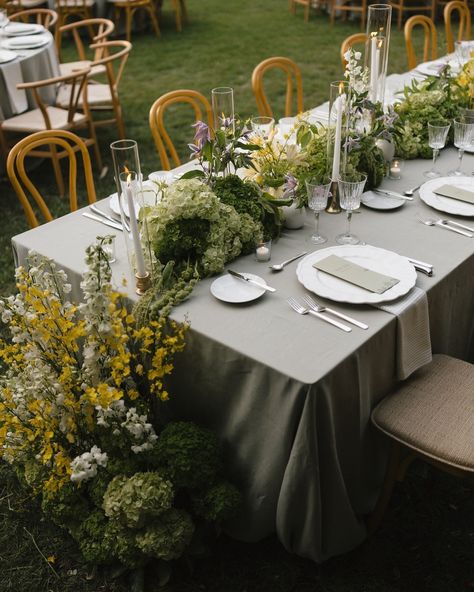 Elegant garden reception table with grey linens, yellow and white floral centerpieces, and bentwood chairs Botanical Wedding Reception, Taper Candle Centerpieces, Outdoor Wedding Tablescapes, Yellow Floral Arrangements, Taper Candle Centerpiece, White Hydrangea Centerpieces, Hydrangea Centerpieces, Outdoor Wedding Decor, Cake Displays