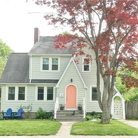 This classic cottage uses pops of color by adding a fun peach color to the front door and royal blue chairs. New England Homes Exterior, Exterior House Paint Schemes, House England, Green House Exterior, Best Exterior House Paint, Benjamin Moore Exterior, Best Exterior Paint, Farmhouse Paint Colors, Exterior Paint Color