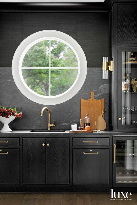 In contrast to the light, bright dining room adjoining it, the wet bar’s dark palette strikes a moodier note. Ebony cerused-oak cabinetry by Pettigrew Cabinets Inc. in Plantersville, Mississippi, mixes with leathered black galaxy granite and a Schumacher sisal wallcovering to reinforce the inky scheme. Both the Water Street Brass hardware and Sub-Zero wine refrigerator are from Ferguson. Bright Dining Rooms, Cerused Oak, Wood Accent Table, Luxe Interiors, Oak Doors, Marble Slab, Interiors Design, Ceiling Beams, Wet Bar